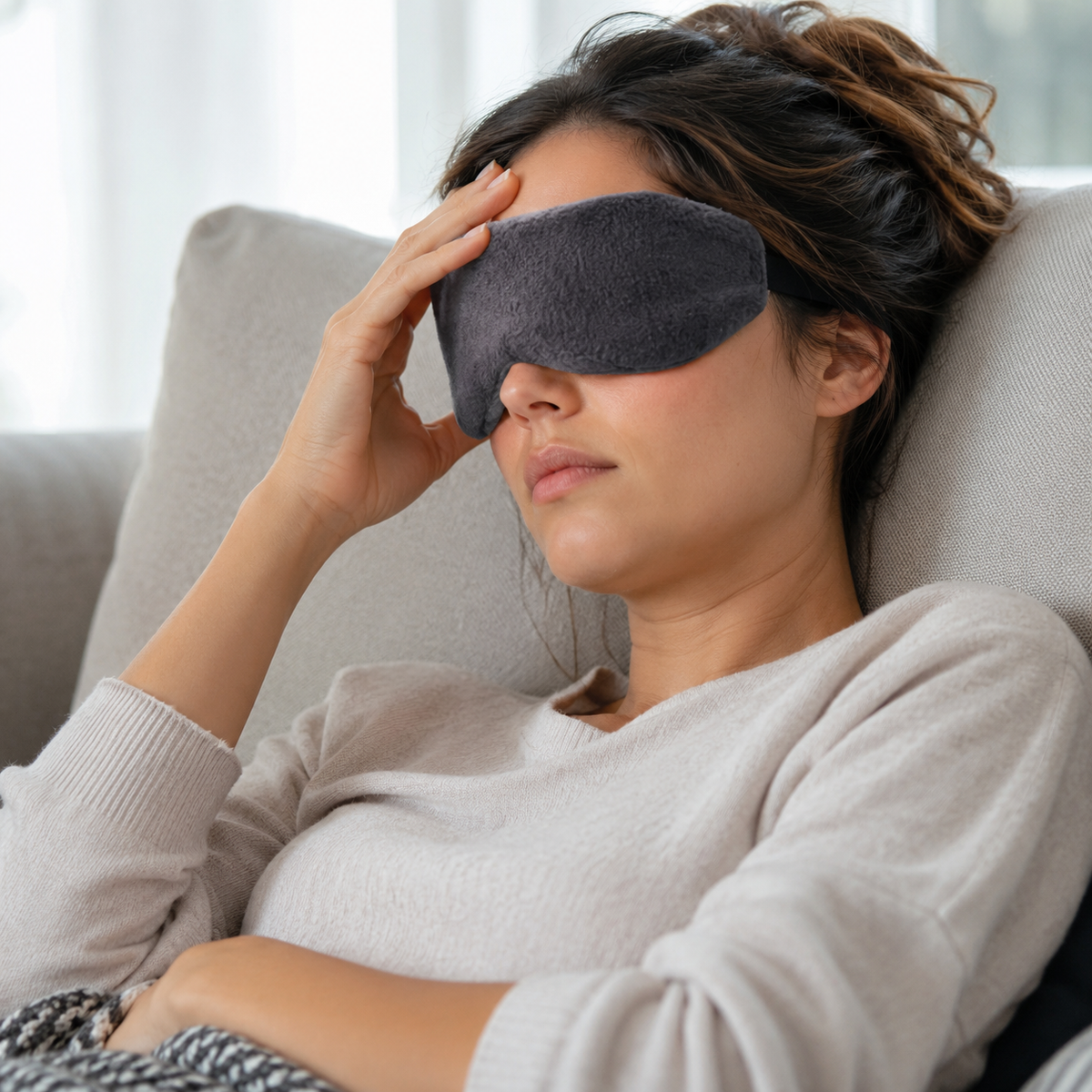 mujer teniendo migraña y alizandola con el antifaz gris para terapia de frio y calor de la marca bella form